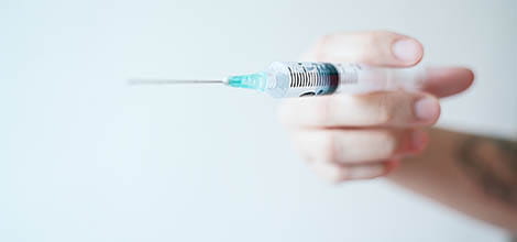 Photo of hand holding syringe vaccination